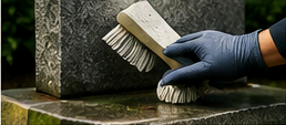 A gloved caretaker gently brushing a stone memorial